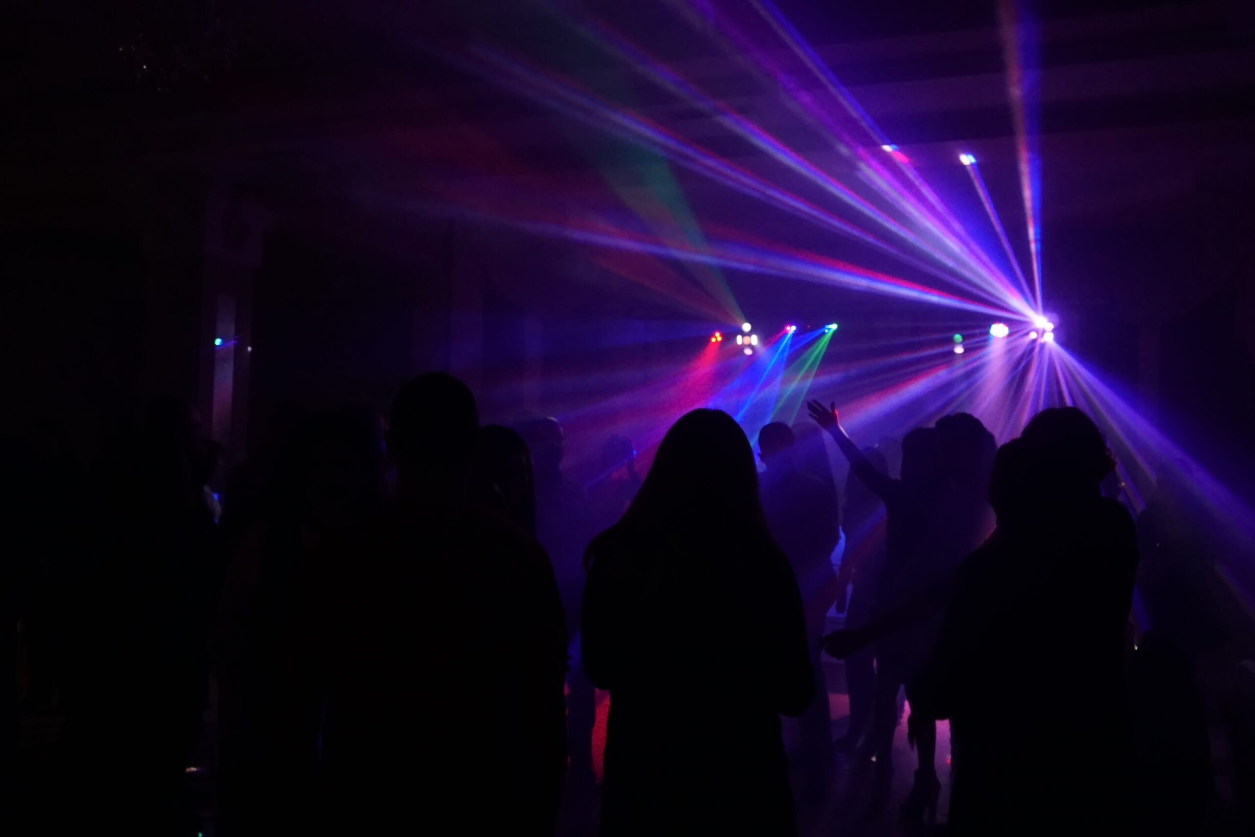 Crowd of people dancing under disco laser light